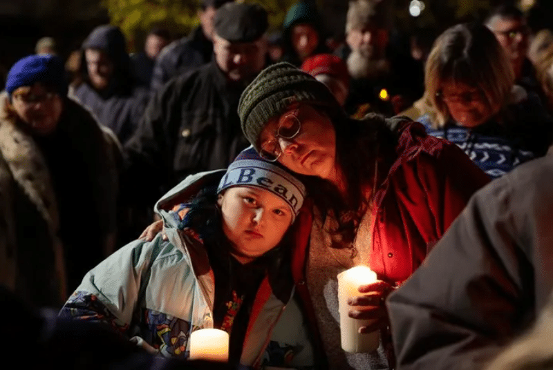 People hold a vigil for the victims of the mass shooting